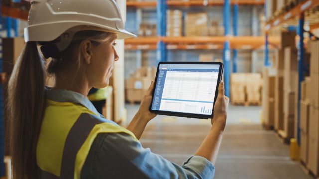 Professional Female Worker Wearing Hard Hat Uses Digital Tablet