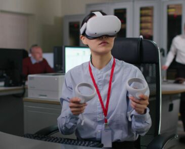 Young woman in formal wear use vr headset and joysticks in modern office. Industrial designer or engineer work in augmented goggles