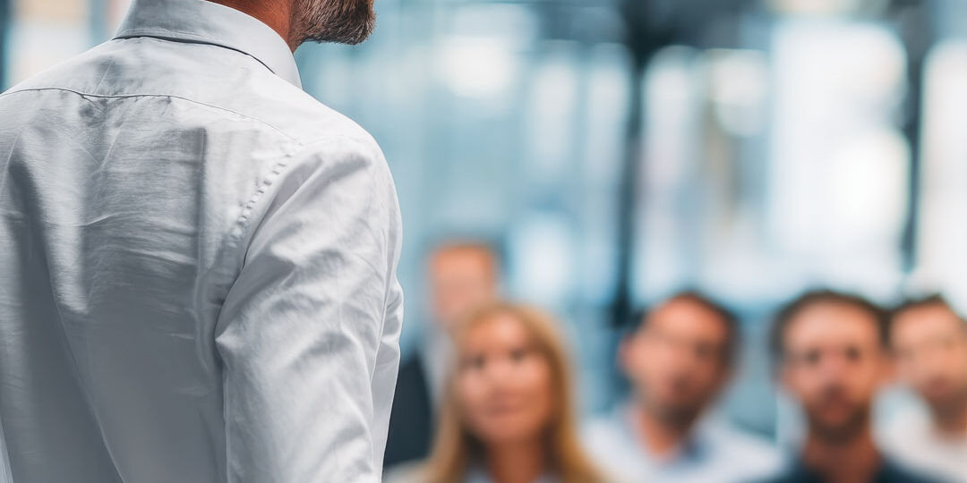 a man stands in front of a group of employees giving a presentat